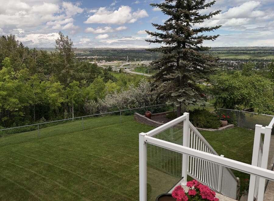 Enjoy breathtaking panoramic views from this stunning property, featuring a meticulously maintained backyard with a lush green lawn and mature trees.