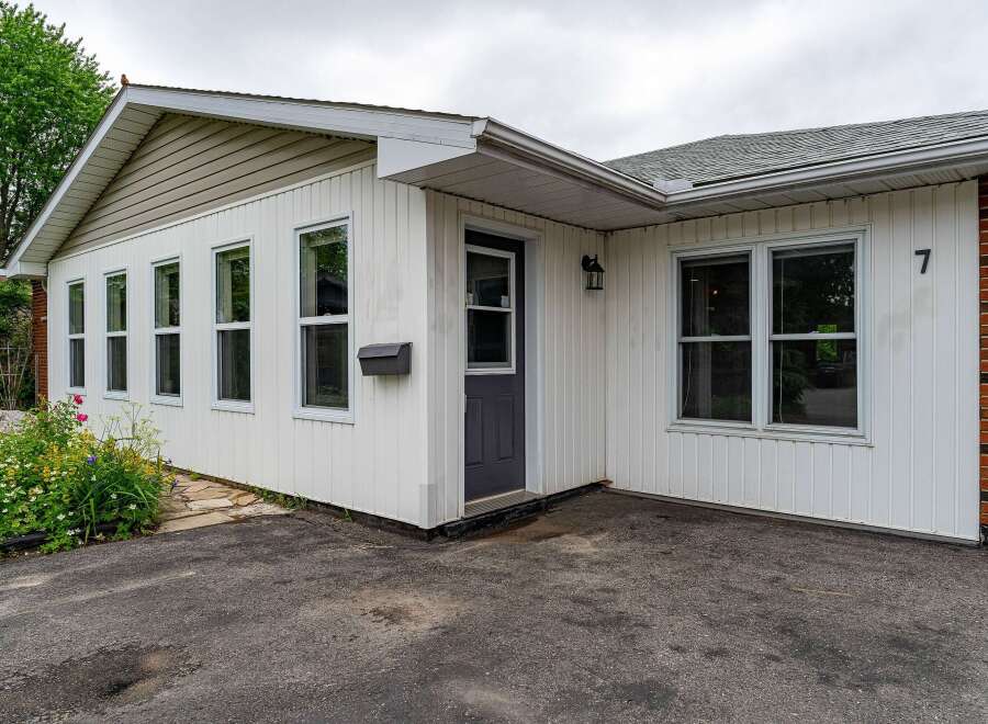 Charming single-family home featuring a welcoming facade with white vinyl siding and a classic brick accent.
