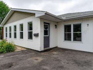 Charming single-family home featuring a welcoming facade with white vinyl siding and a classic brick accent.