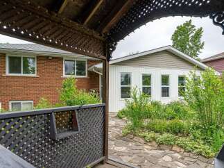 Step into a charming backyard oasis featuring a rustic wooden pergola and a lush garden path.