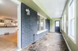 Step into this charming sunroom, featuring a unique flagstone floor and a striking dark brick accent wall.