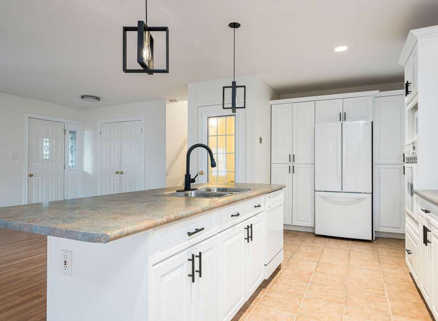 Discover this beautifully renovated kitchen featuring a spacious island with a double sink and a sleek black faucet.