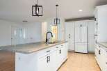 Discover this beautifully renovated kitchen featuring a spacious island with a double sink and a sleek black faucet.