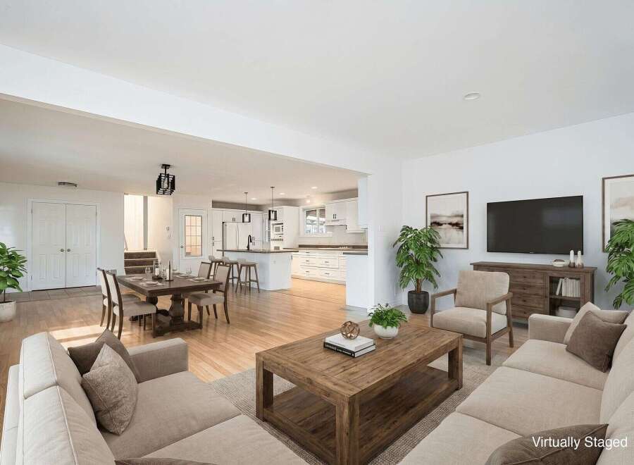 Experience seamless open-concept living in this beautifully staged home, featuring a spacious dining area adjacent to a modern white kitchen with ample counter space and bar seating.