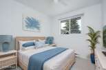 Experience coastal charm in this serene bedroom, featuring a light and airy atmosphere with a woven headboard and calming blue accents.