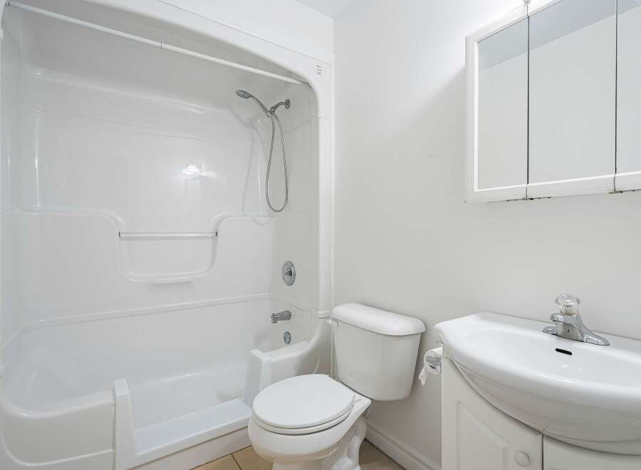 This bright and clean bathroom features a pristine white bathtub and shower combination, perfect for relaxing baths or quick rinses.