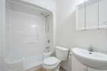 This bright and clean bathroom features a pristine white bathtub and shower combination, perfect for relaxing baths or quick rinses.