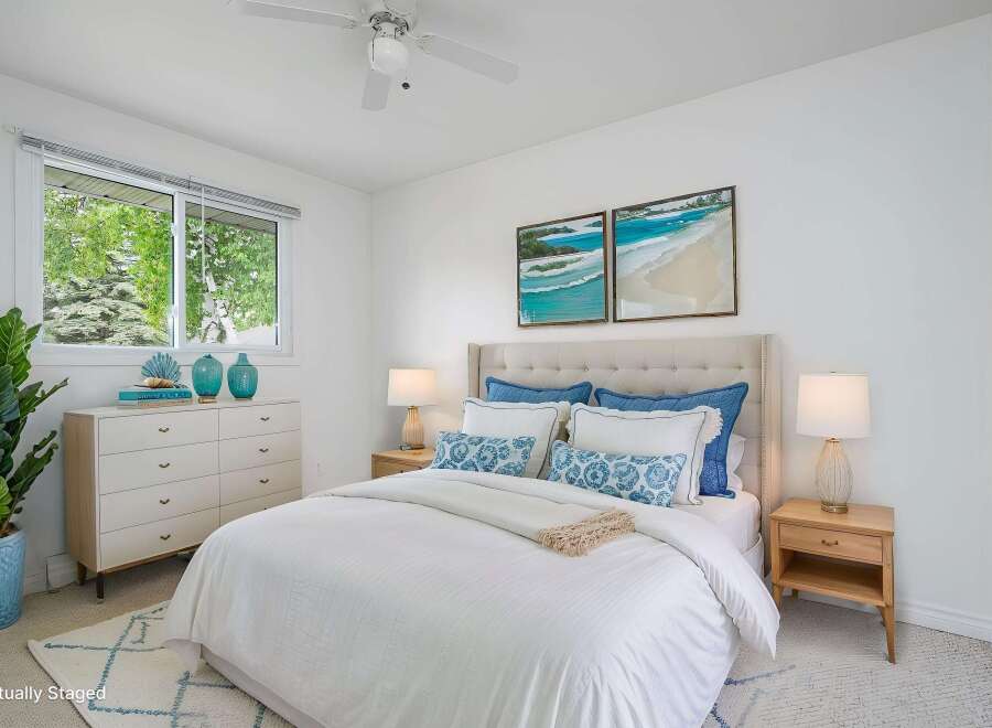 Experience coastal serenity in this beautifully staged bedroom, featuring a plush tufted headboard and crisp white linens.