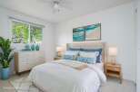 Experience coastal serenity in this beautifully staged bedroom, featuring a plush tufted headboard and crisp white linens.