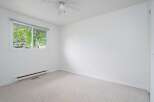 This bright and airy bedroom features a large window offering abundant natural light and views of lush greenery.
