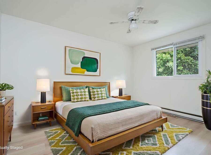 This beautifully staged bedroom features a modern wooden bed frame complemented by a vibrant abstract art piece and a plush geometric rug.
