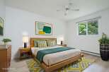 This beautifully staged bedroom features a modern wooden bed frame complemented by a vibrant abstract art piece and a plush geometric rug.
