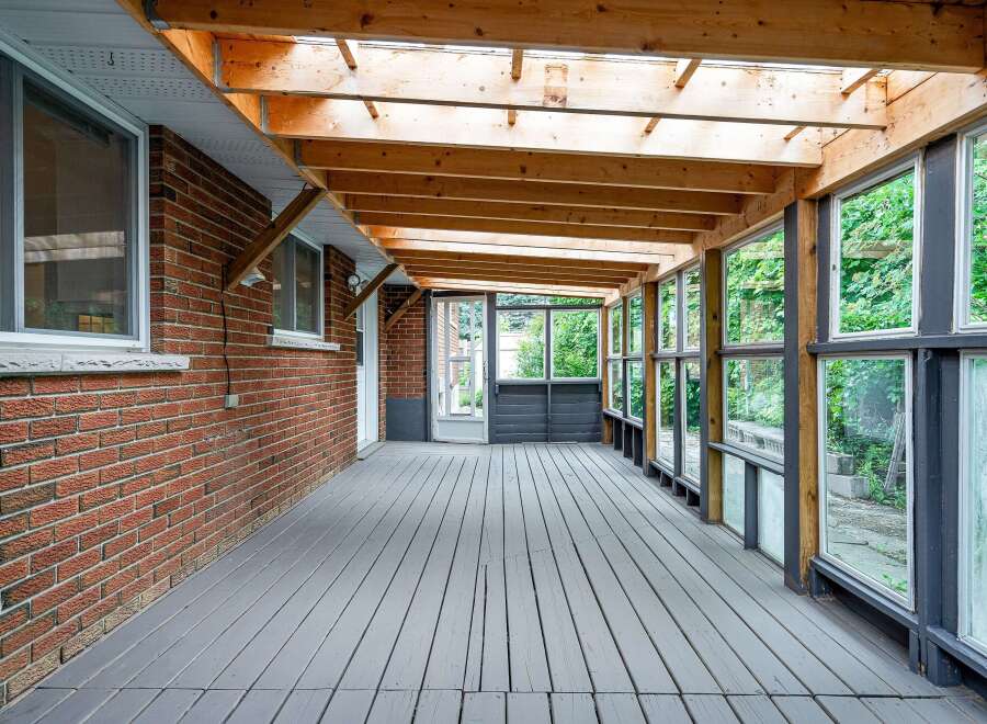 Enjoy the outdoors in this charming sunroom, featuring a spacious wooden deck and a glass-enclosed ceiling that floods the space with natural light.