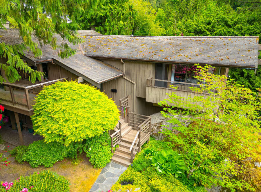 Nestled amidst lush greenery, this charming home offers a serene retreat with its natural wood siding and expansive decks perfect for outdoor living.