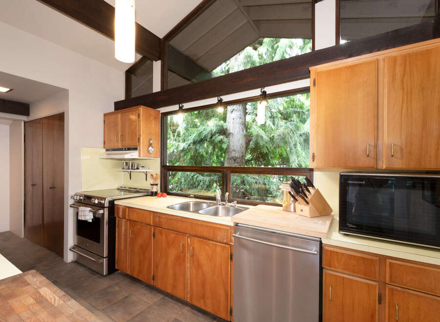 Experience the charm of this kitchen, featuring warm wood cabinetry and a stunning large window overlooking lush greenery.