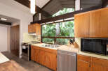 Experience the charm of this kitchen, featuring warm wood cabinetry and a stunning large window overlooking lush greenery.