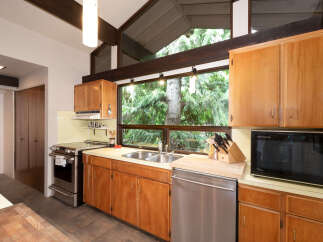 Experience the charm of this kitchen, featuring warm wood cabinetry and a stunning large window overlooking lush greenery.
