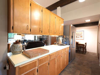 This spacious kitchen features warm wooden cabinetry, a large butcher block, and a sleek stainless steel refrigerator.