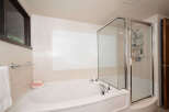 Indulge in relaxation with this luxurious corner bathtub, featuring a separate glass-enclosed shower for ultimate convenience.