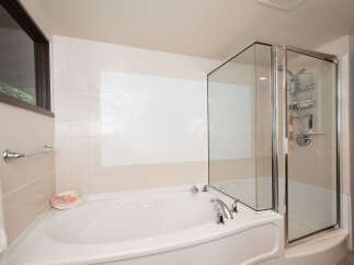 Indulge in relaxation with this luxurious corner bathtub, featuring a separate glass-enclosed shower for ultimate convenience.