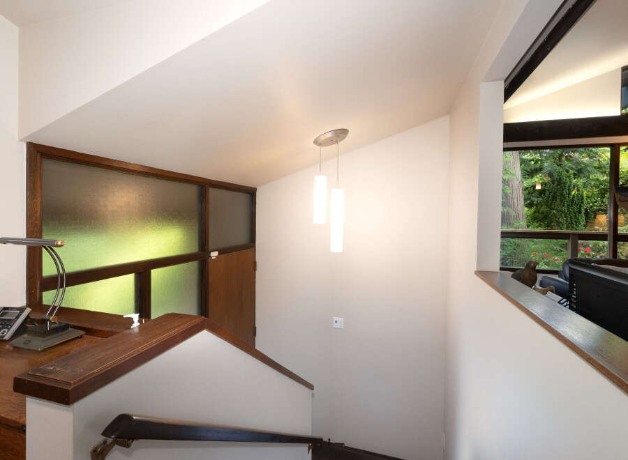 Experience the unique architectural design of this home, featuring a striking staircase with rich wood accents and a frosted glass window that bathes the space in natural light.