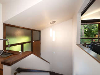 Experience the unique architectural design of this home, featuring a striking staircase with rich wood accents and a frosted glass window that bathes the space in natural light.