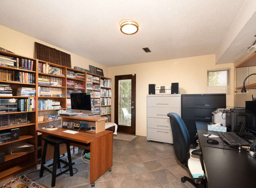 This home office features extensive built-in bookshelves filled with a diverse collection of books, creating a studious and organized atmosphere.