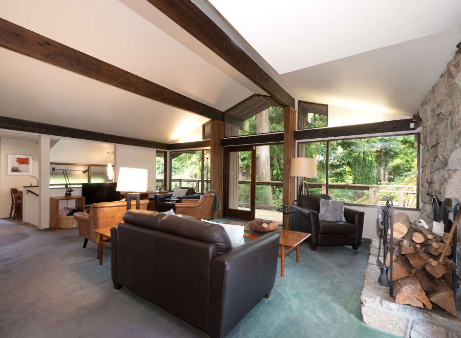 Experience rustic charm in this spacious living room, featuring exposed wooden beams and a magnificent stone fireplace.