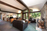 Experience rustic charm in this spacious living room, featuring exposed wooden beams and a magnificent stone fireplace.