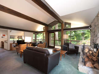 Experience rustic charm in this spacious living room, featuring exposed wooden beams and a magnificent stone fireplace.