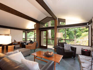 Experience the ultimate in rustic charm with this stunning living room, featuring soaring vaulted ceilings with exposed wooden beams and a magnificent stone fireplace.