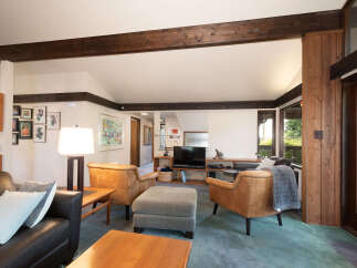 Experience the warmth of this inviting living room, featuring rich wood beams and a cozy seating arrangement.