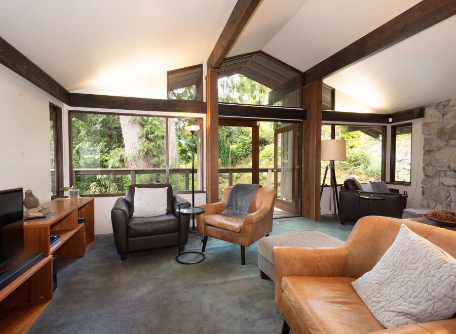 Experience the ultimate in relaxation with this stunning living room, featuring a cozy stone fireplace and large windows that offer breathtaking views of the surrounding greenery.
