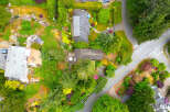 Discover this stunning aerial view showcasing a beautifully landscaped property with multiple homes nestled amongst lush greenery and vibrant flowering bushes.