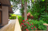Enjoy the lush greenery and vibrant blooms from this stunning property's expansive wooden deck.