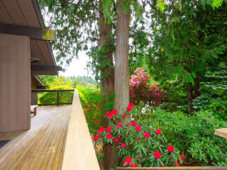 Enjoy the lush greenery and vibrant blooms from this stunning property's expansive wooden deck.