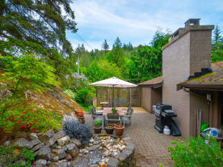 Enjoy outdoor living with this charming patio featuring a dining set under a large umbrella, a built-in barbecue grill, and a cozy swing set.