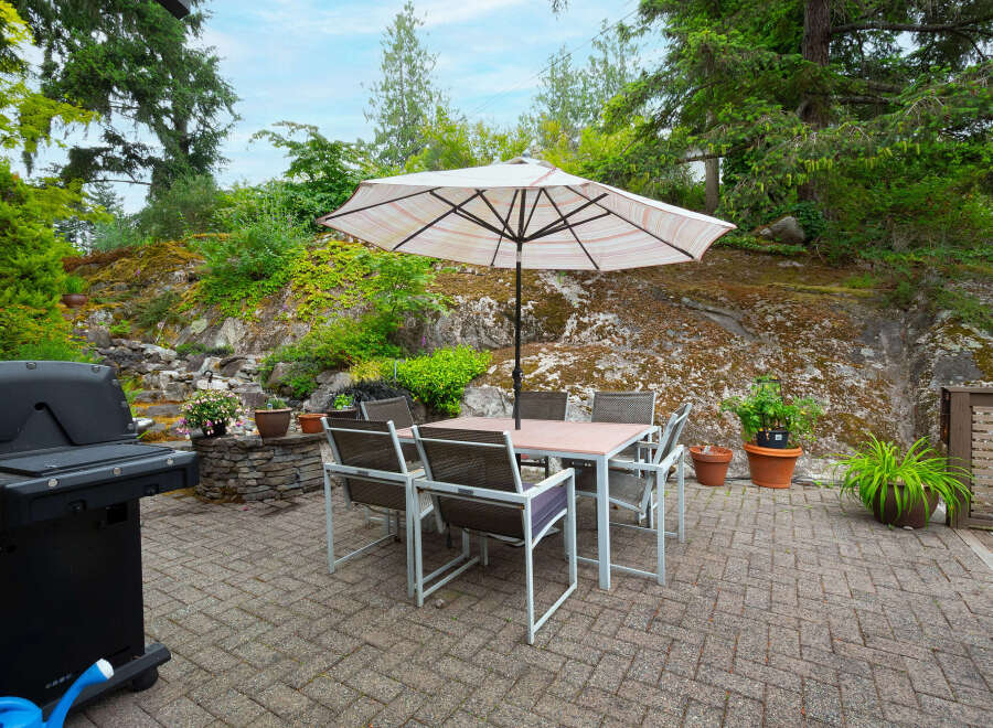 Enjoy outdoor living with this spacious patio featuring a dining set and umbrella, perfect for al fresco meals.