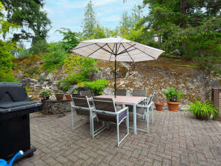 Enjoy outdoor living with this spacious patio featuring a dining set and umbrella, perfect for al fresco meals.
