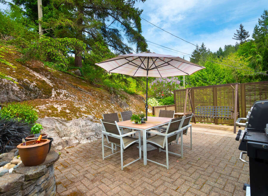 Enjoy outdoor living with this charming patio featuring a dining set under a large umbrella, perfect for al fresco meals.