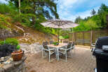 Enjoy outdoor living with this charming patio featuring a dining set under a large umbrella, perfect for al fresco meals.