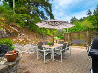 Enjoy outdoor living with this charming patio featuring a dining set under a large umbrella, perfect for al fresco meals.