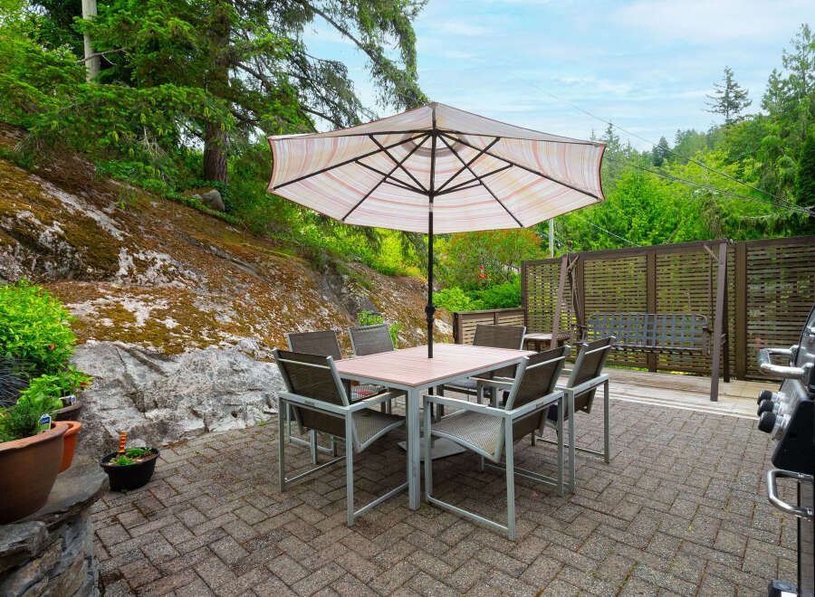 Enjoy outdoor living with this spacious patio featuring a dining set and umbrella, perfect for al fresco meals.