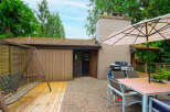 Enjoy outdoor living with this spacious patio featuring a dining set under an umbrella, a grill for cookouts, and a swing set for relaxation.