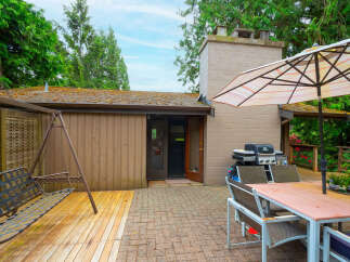 Enjoy outdoor living with this spacious patio featuring a dining set under an umbrella, a grill for cookouts, and a swing set for relaxation.