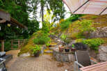Discover this stunning outdoor oasis, featuring a multi-level stone pathway winding through lush greenery and leading to a charming wooden deck.