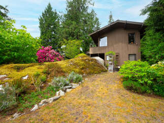 Nestled amidst lush greenery and vibrant rhododendrons, this charming home offers a serene retreat.