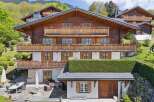 Experience luxury mountain living in this stunning chalet, featuring multiple balconies adorned with vibrant flower boxes and expansive windows offering breathtaking views.