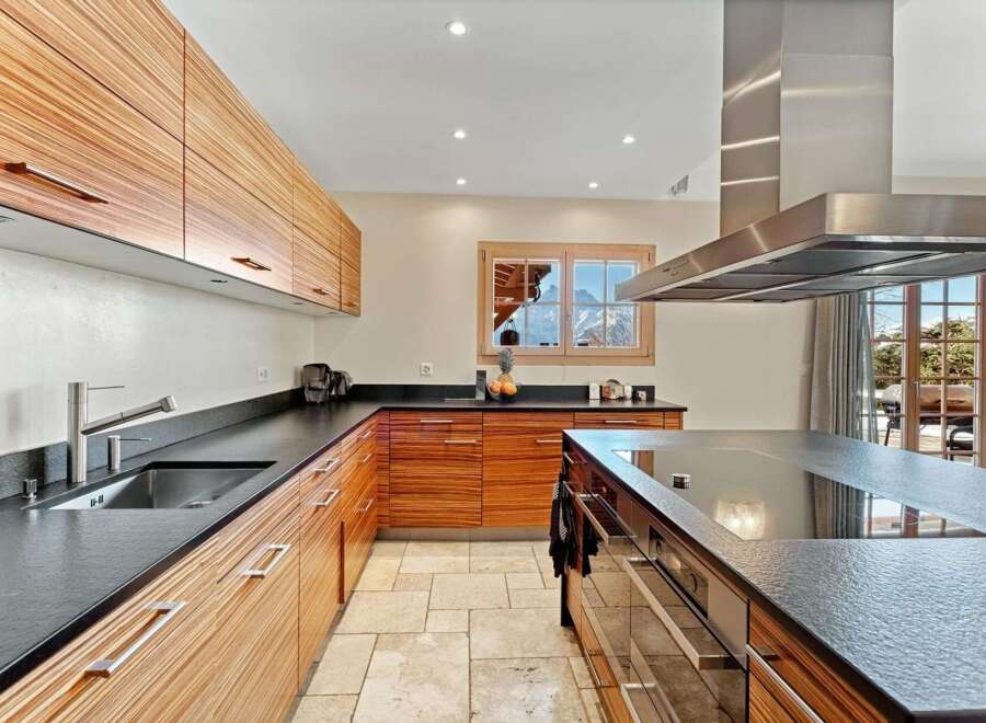 Experience luxury mountain living in this stunning kitchen featuring sleek, wood-grain cabinetry and expansive dark countertops.