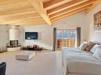 Experience luxury mountain living in this stunning bedroom featuring a modern fireplace and a wall-mounted TV.